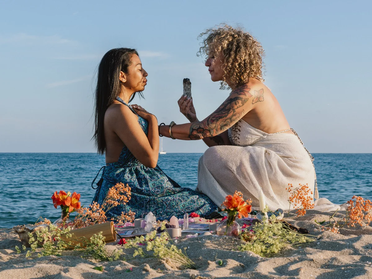 Sandra BZ realitzant un ritual amb una altra dona a la platja